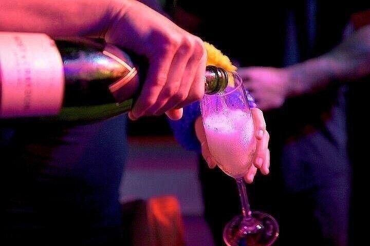 Sparkling wine poured into a glass under coloured light