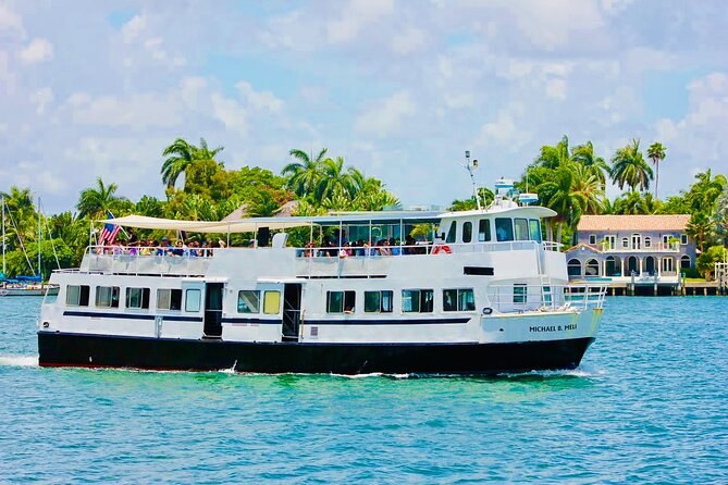 A white two-deck sightseeing boat on turquoise water past waterfront homes
