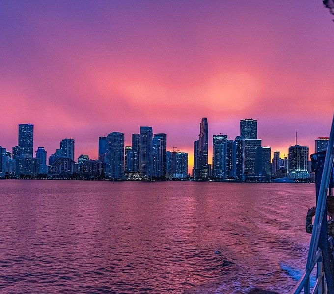 The skyline in silhouette under a pink dusk sky, seen from the deck of a boat