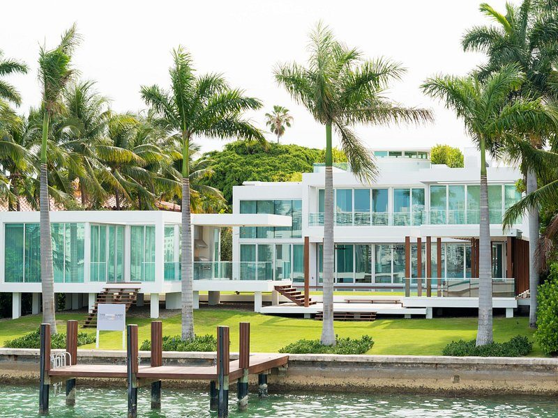 A white modern villa among palms, its own dock on the water